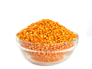 Red raw lentils in a glass bowl. Isolated on white background