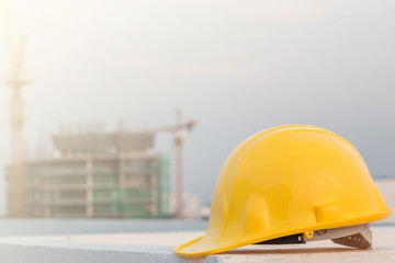 The yellow safety helmet and the blueprint at construction site with crane background