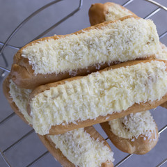 Cake eclair with citrus cream and coconut chips.