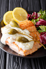 creamy lemon garlic salmon piccata with fresh mix salad closeup on a plate. Vertical