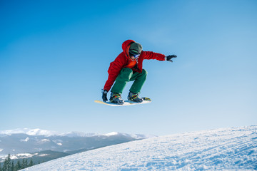 Fototapeta na wymiar Snowboarder makes a jump on speed slope