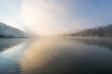 Fototapeta na wymiar Sonnenaufgang mit Nebel am See in den Bergen