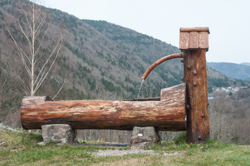 Obraz premium typical wooden fountain on moutain landscape background