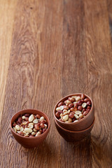 Two ceramic bowls with raw peanuts mix isolated over rustic wooden backround, top view, close-up.