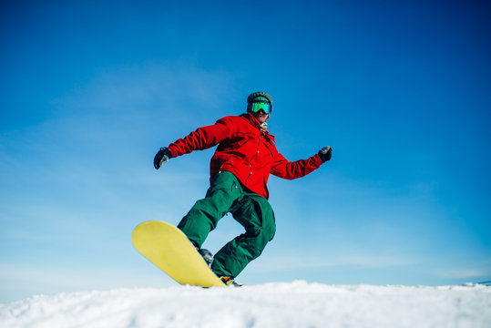 Snowboarder in glasses poses with board in hands