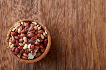 Two ceramic bowls with raw peanuts mix isolated over rustic wooden backround, top view, close-up.