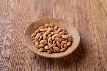 Bowl of almonds on wooden background, top view, close-up, selective focus.