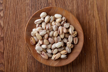 Almonds in brown bowl on wooden background, top view, selective focus.