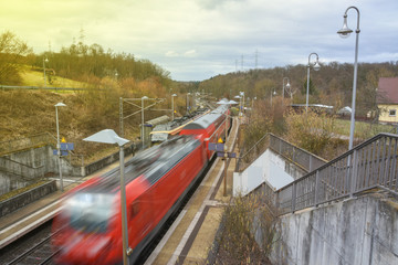 Fototapeta na wymiar Rote Eisenbahn fährt durch Bahnhofstation in voller Geschwindigkeit