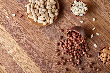 A composition from different varieties of nuts in a wooden bowls on rustic background, close-up, shallow depth of field