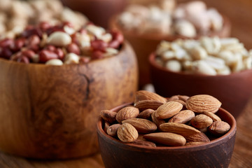 A composition from different varieties of nuts in a wooden bowls on rustic background, close-up, shallow depth of field