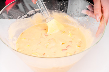 Woman mixes apples and raw dough for apple cake