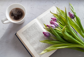Coffee mug with purple tulip flowers on a gray concrete background from above, breakfast. Good morning