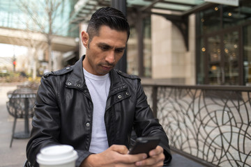 HIspanic man in city using cell phone