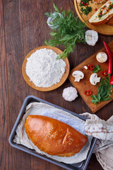 Delicious rustic pastries filled with herbs and vegetables on a wooden plate over a vintage background, selective focus