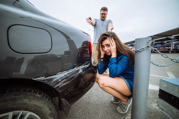 sad woman near scratched car. man shouting on woman. car acciden