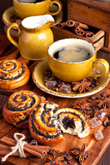 Baked sweet buns with poppy and coffee on wood table