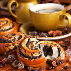 Baked sweet buns with poppy and coffee on wood table