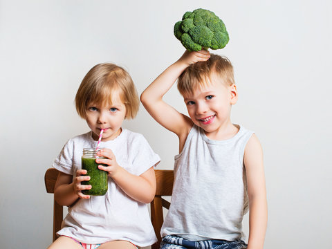 Two Pretty Fun Kids With Green Smoothies And Broccoli. Helthy And Clean Food For Children