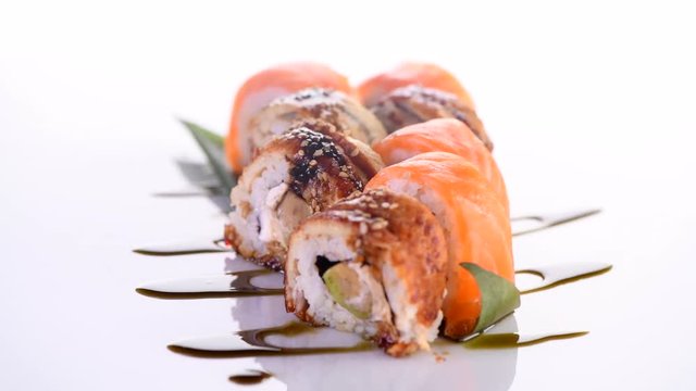 Sushi roll set on white background. Rotated rolls with salmon, tuna, eel, flying fish caviar closeup. Japan restaurant menu. 4K UHD video footage. 3840X2160