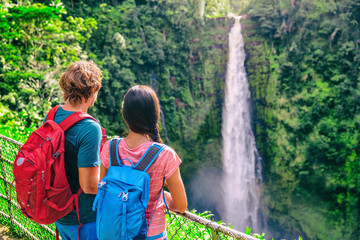 Hawaii travel tourists at nature waterfall landscape. Travelers couple looking at Akaka Falls in Big Island, Hawaiian famous attraction, USA.
