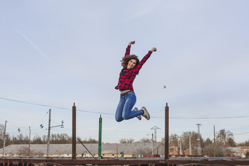 young beautiful woman jumping and feeling happy. She is wearing casual clothes. Outdoors city...