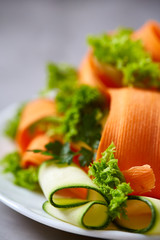 Artistically served vegetable salad with carrot, cucumber, letucce over white background, selective focus