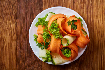 Artistically served vegetable salad with carrot, cucumber, letucce over wooden background,...