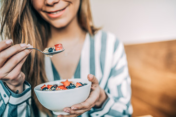 Crop woman close up eating oat and fruits bowl for breakfast