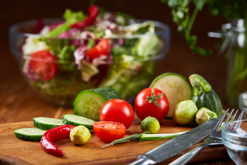 Fresh vegetable salad and ripe veggies on cutting board over wooden background, close up, selective focus