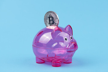 Sparschwein mit einem Bitcoin vor einem blauen Hintergrund