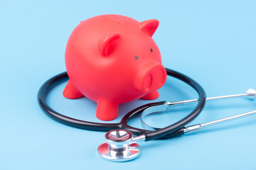 Sparschwein mit einem Stethoskop vor einem blauen Hitergrund