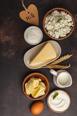 Different types of dairy products on dark background, top view, copy space.