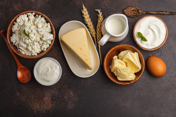 Different types of dairy products on dark background, top view, copy space. Healthy food background.