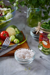 Fresh vegetable salad and ripe veggies on cutting board over white background, close up, selective focus