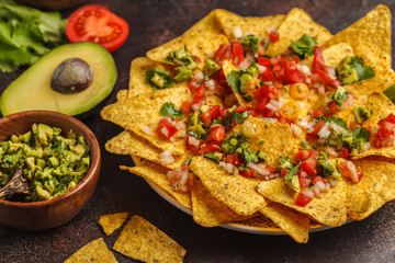Mexican food concept. Nachos - yellow corn totopos chips with various sauces in wooden bowls: guacamole, cheese sauce, pico del gallo