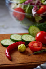 Fresh vegetable salad and ripe veggies on cutting board over white background, close up, selective focus