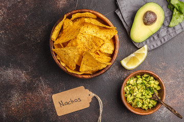 Mexican food concept. Nachos - yellow corn totopos chips with guacamole, frame of food, top view, copy space.
