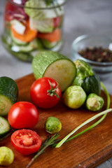 Fresh vegetable salad and ripe veggies on cutting board over white background, close up, selective focus