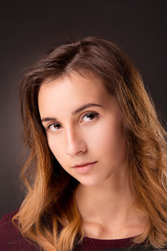 A brunette girl with clean skin close-up on a dark background.