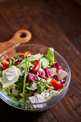 Delicious vegetable salad in jar and fresh veggies on cutting board on table, selective focus, close-up