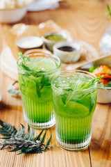 Green lemonade with tarragon, lime and ice on wooden background