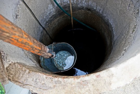 iron bucket with water at the depth of a round well