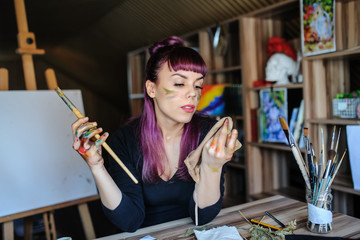 female artist with purple hair and dirty hands