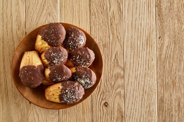 Freshly baked almond cookies piled on ceramic plate over white background, top view, close-up, selective focus