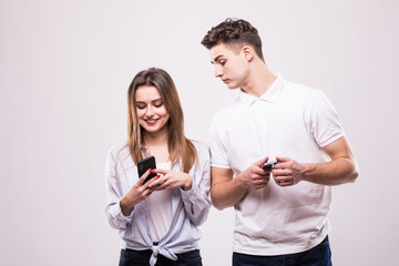 Close up portrait of a interracial smiling couple using mobile phones isolated on the gray background. Man look at woman phones