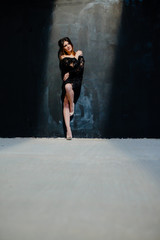 Fototapeta na wymiar Brunette posing near black wall in the studio