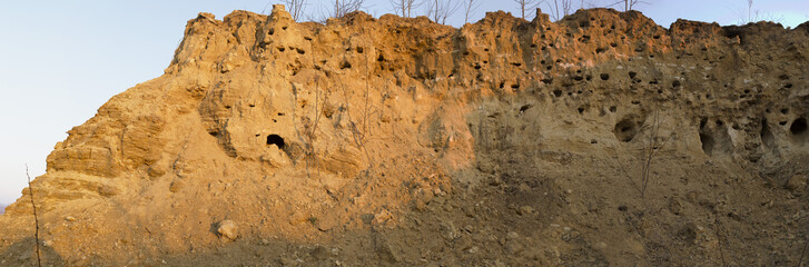 The South gorge where nesting Swifts. Red hills with caves. Quarry during sunset.
