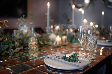 Mirror table served with plates, forks, spoons, glasses,  napkins in the restaurant. Beautiful festive table decorated with fresh flowers and candles