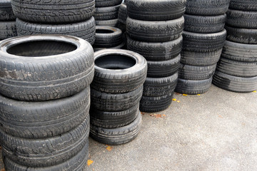 Used car tires stacked in piles at junkyard. Old wheels recycling and utilization